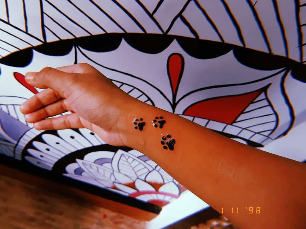 A forearm adorned with three cat paw print tattoos