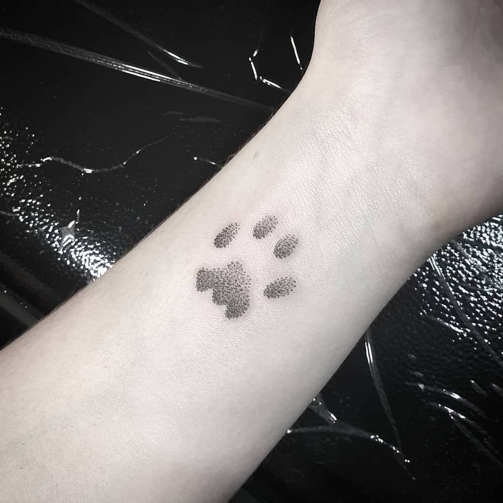 A small cat paw tattoo on the inner wrist