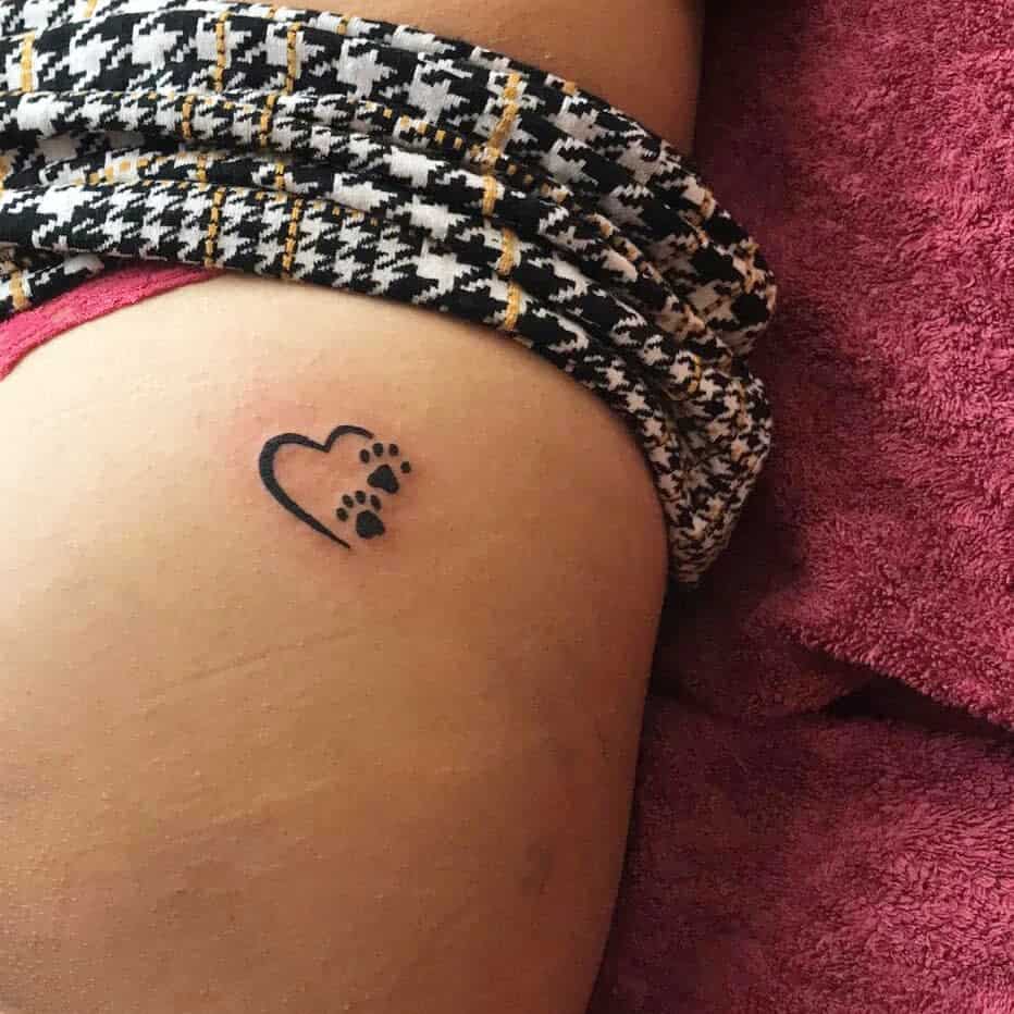 A small heart tattoo with cat paw prints on an upper thigh