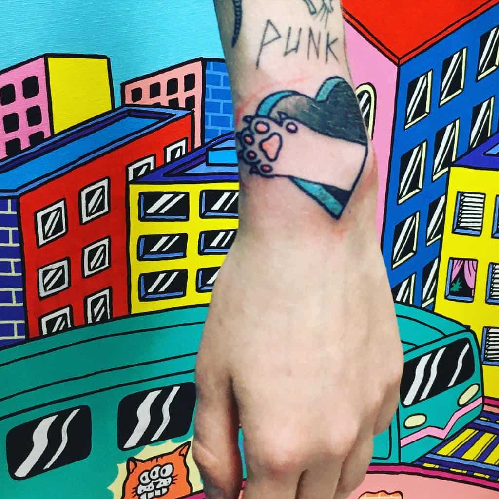 Tattoo of a cat paw inside a heart on a wrist