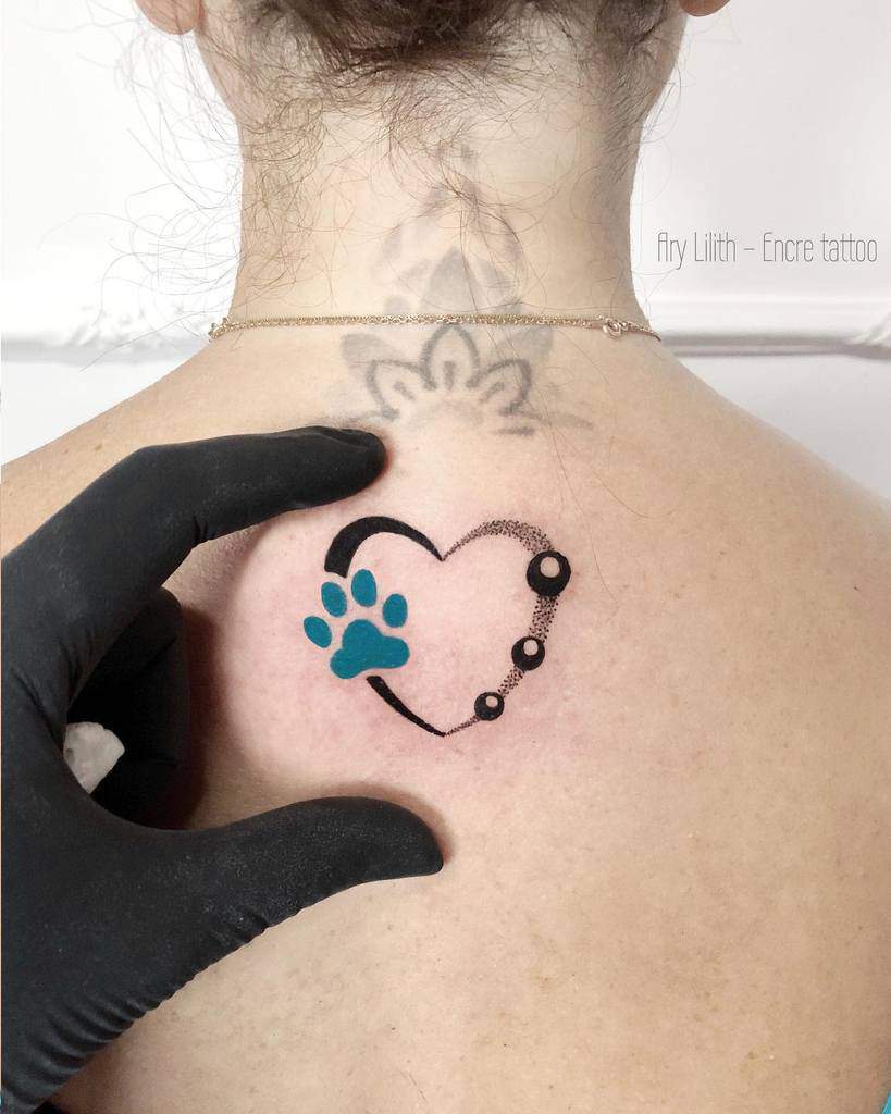 A tattoo of a heart featuring a cat paw on an upper back