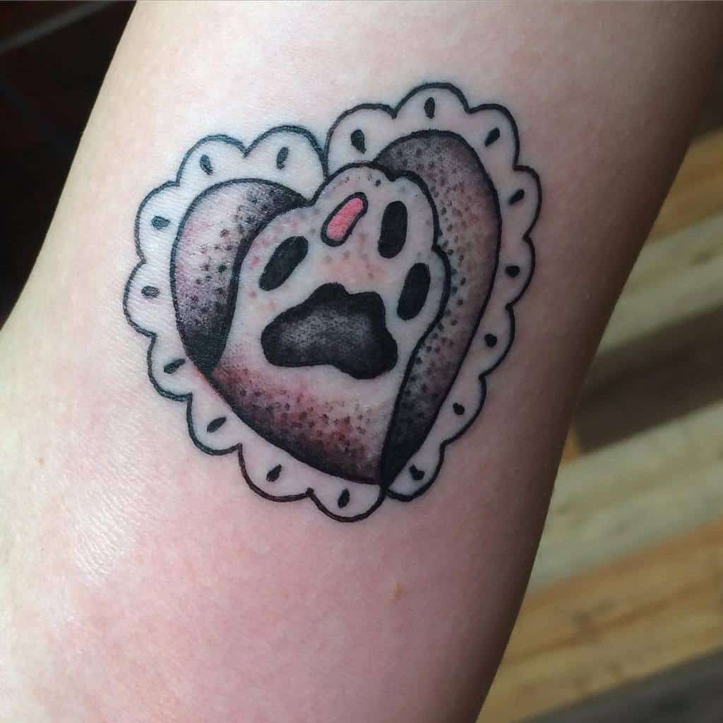Tattoo of a heart-shaped cat paw print encased in delicate lace on a person's skin