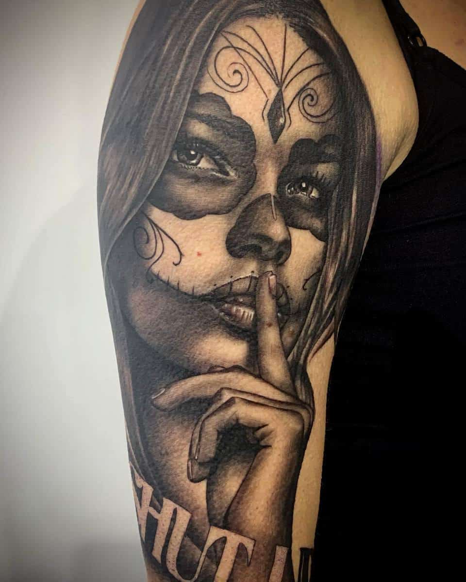 A realistic black-and-grey Catrina tattoo with intricate face paint, symbolizing silence and the Day of the Dead