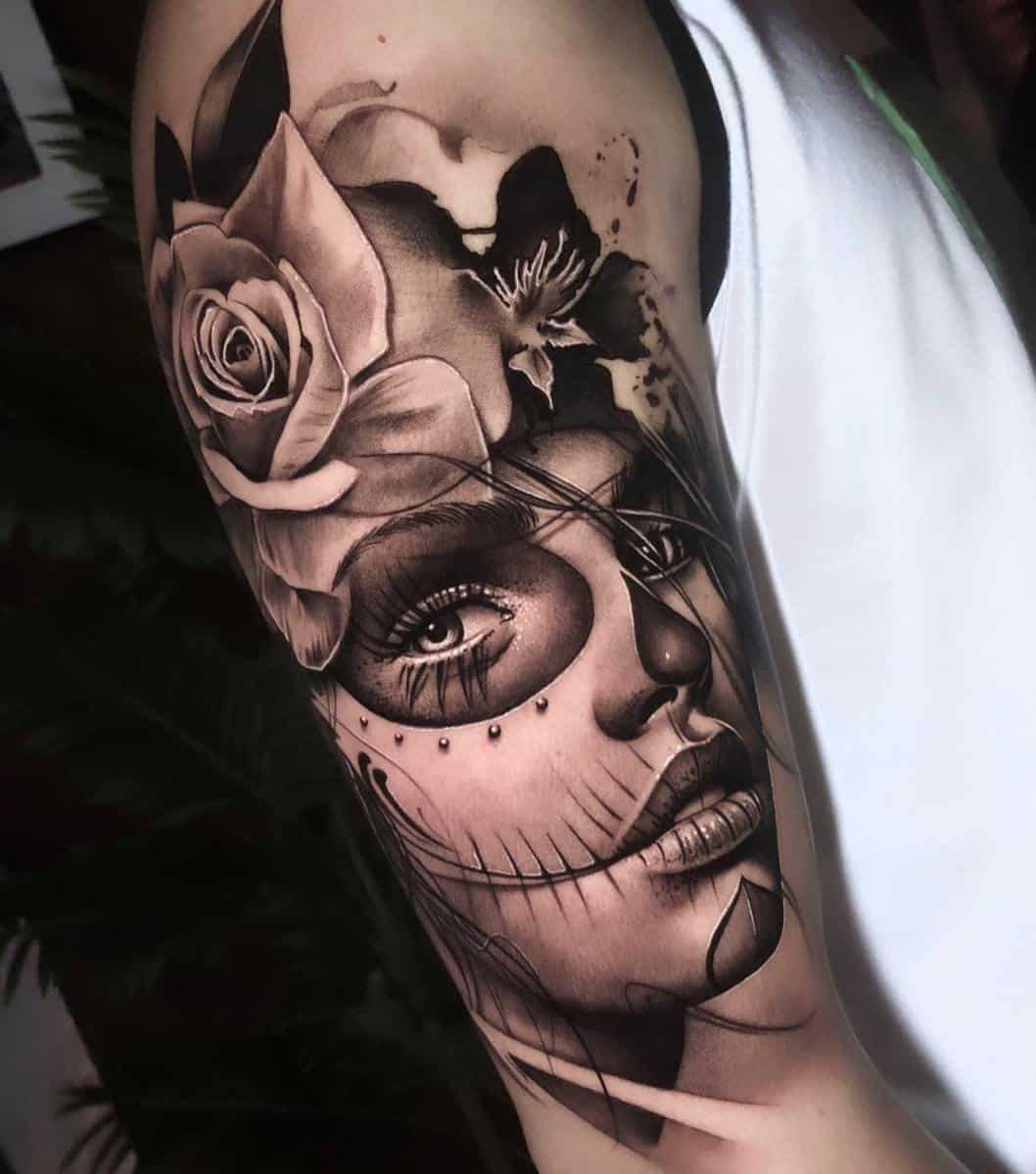 A striking Catrina tattoo featuring a woman's face with sugar skull makeup, adorned with a large rose