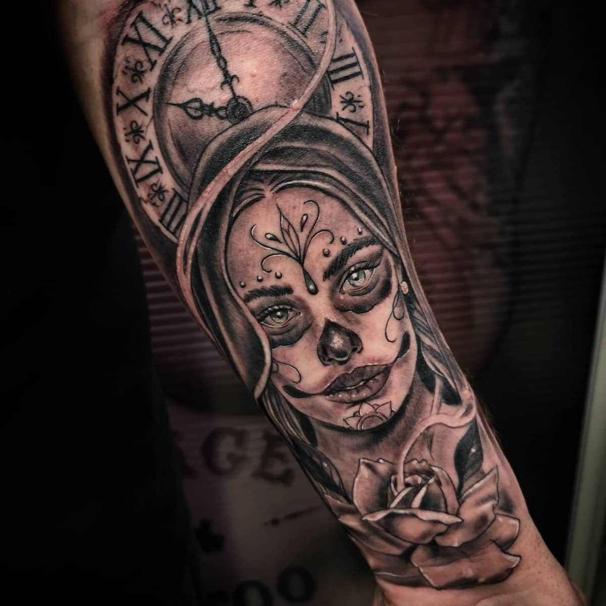 Black-and-grey Catrina tattoo showing a woman adorned with a clock and a rose, symbolizing time and beauty