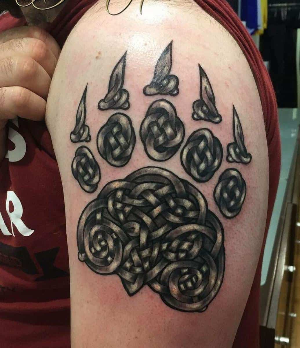 An intricate bear paw tattoo on a person's upper arm