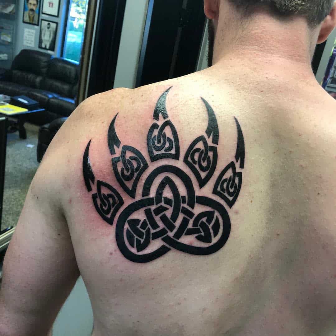 Man with a large, intricate bear paw tattoo on his upper back
