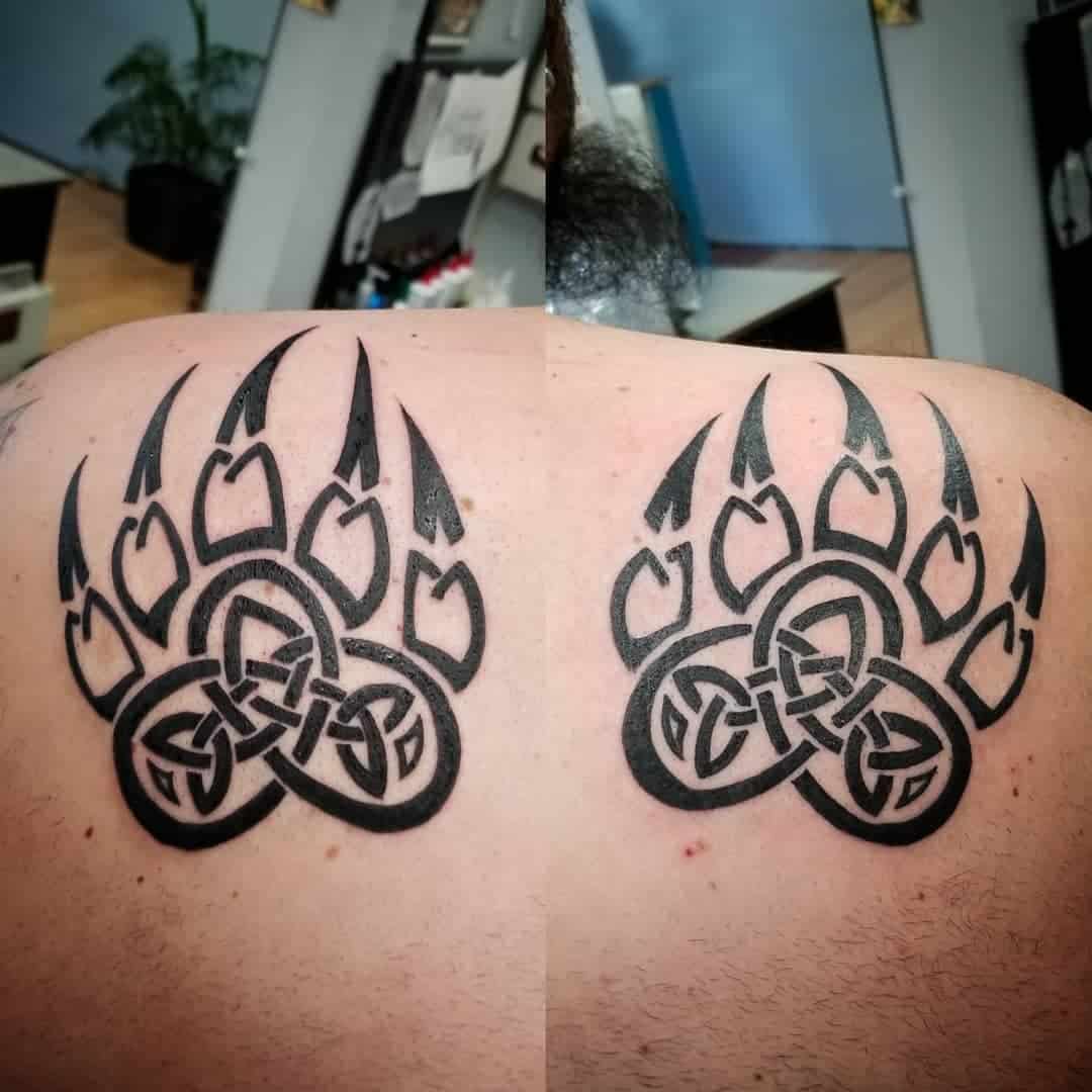 Two identical Celtic knot bear paw tattoos on a person's upper back