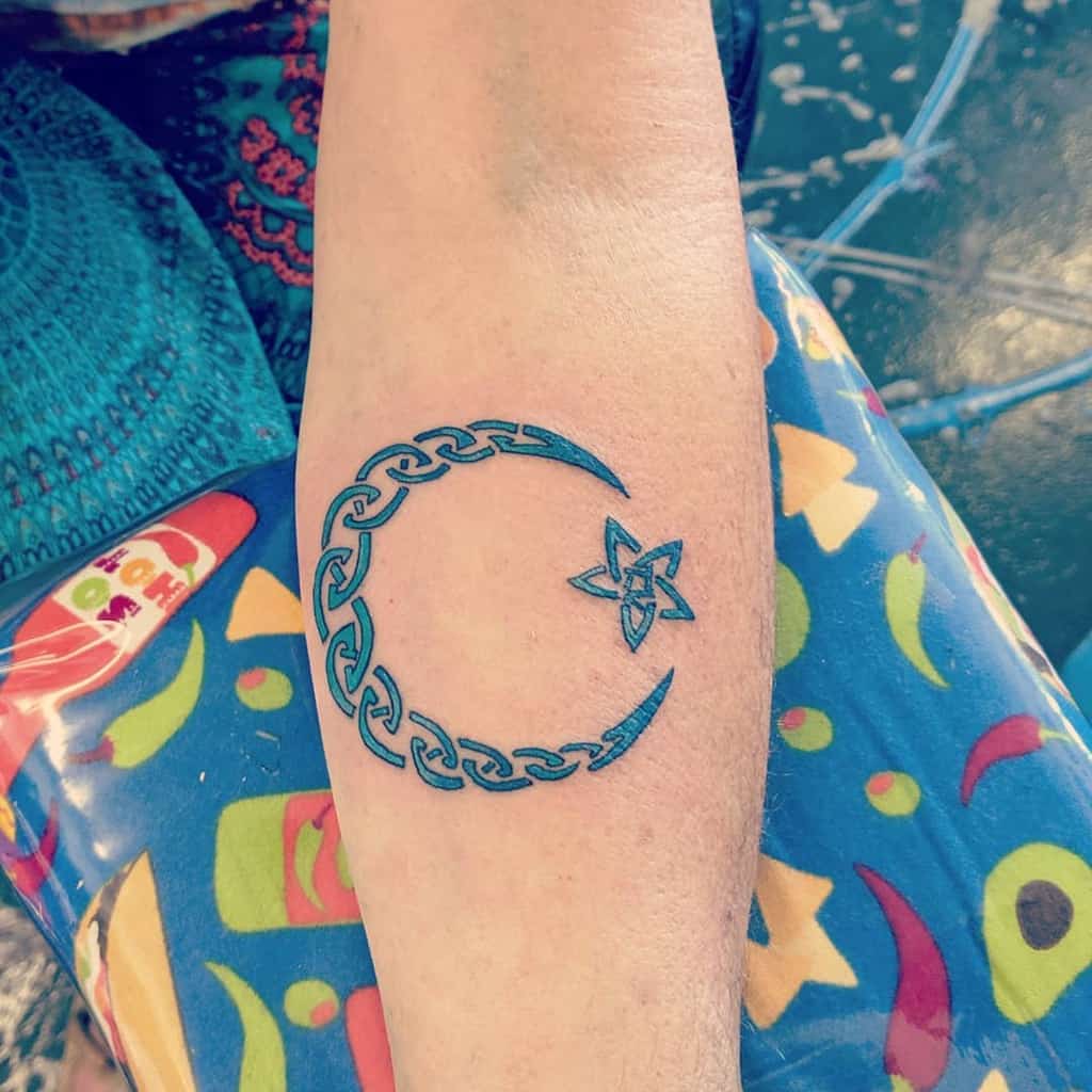 Tattoo of a crescent moon and a star with Celtic designs on a person's forearm blending celestial elegance with detailed artistry