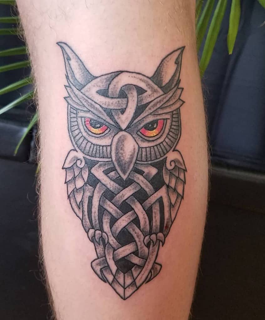 Black and grey Scottish owl tattoo with Celtic knotwork forming its body, intense red eyes, and intricate shading for a bold, mystical look