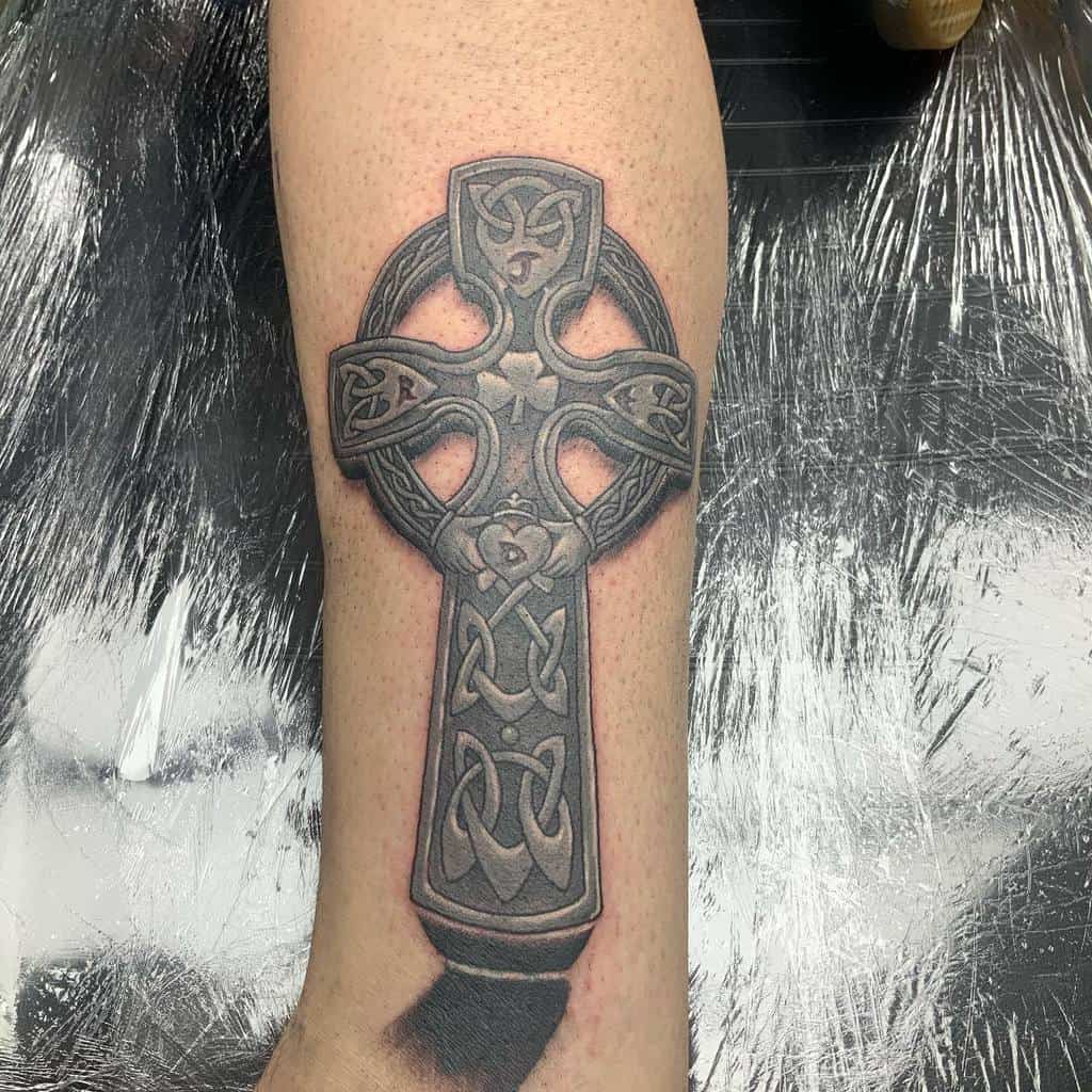 Black and grey Scottish Celtic cross tattoo with intricate knotwork and a shamrock at the center