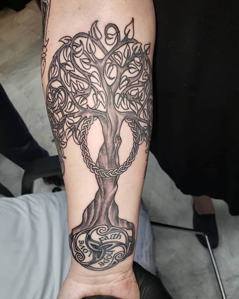 Tree of life Scottish tattoo with intricate branches, braided trunk, and 'Love, Faith, Hope' inscribed within a swirling base design