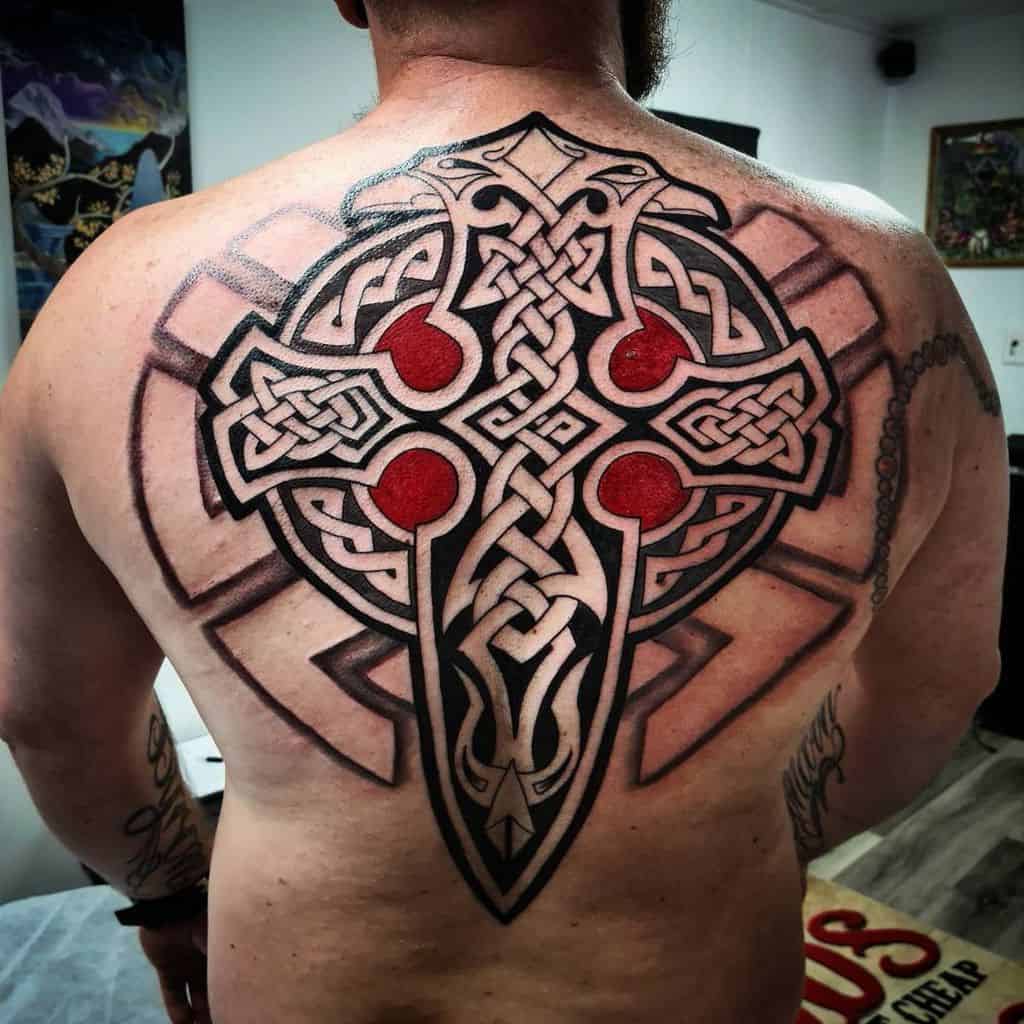 A large Celtic cross tattoo covering the upper back, featuring intricate knotwork and red accents within the cross design