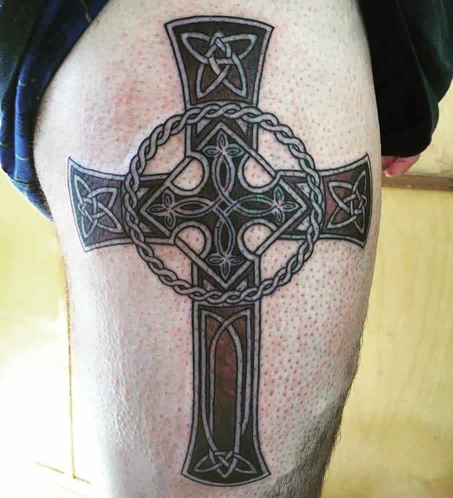 Celtic tattoo on a forearm featuring an intricate cross with knot patterns and circular designs