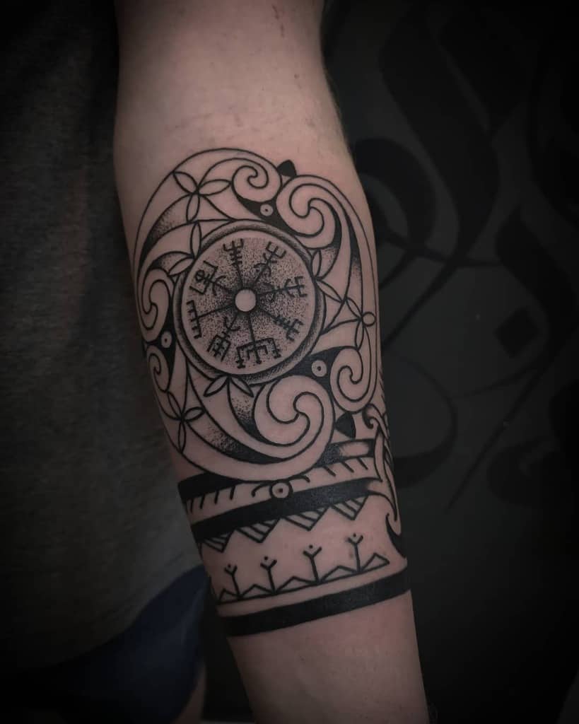 A forearm tattoo featuring the Vegvisir symbol surrounded by swirling knotwork patterns, bold geometric lines, and tribal elements