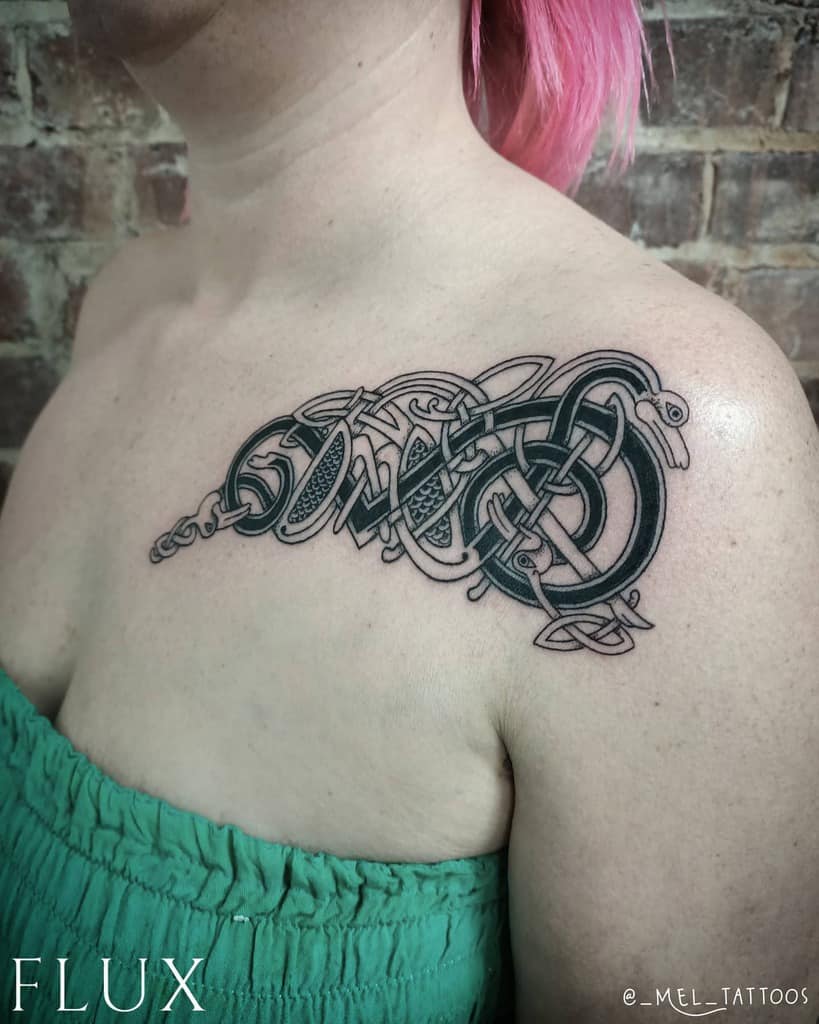 A Celtic-inspired tattoo on the shoulder featuring intricate knotwork with a snake design woven through the pattern