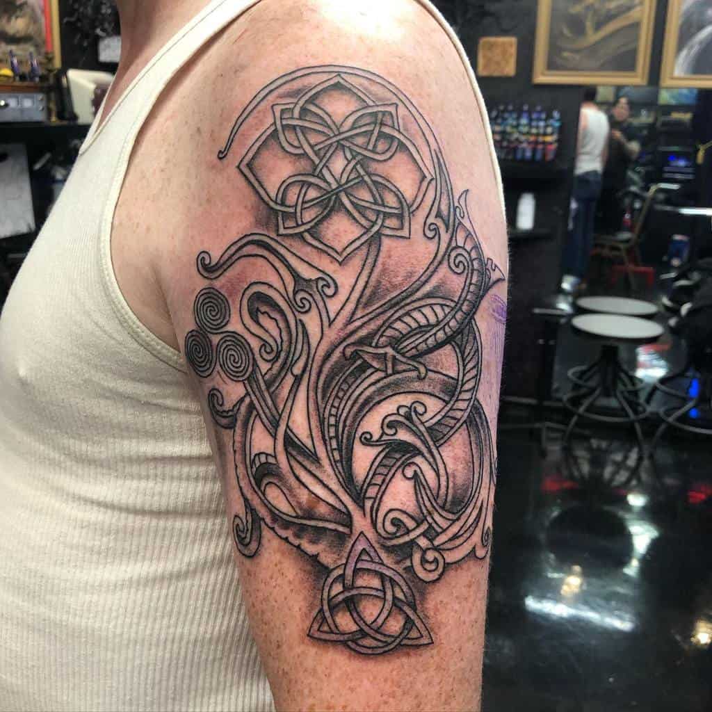 A Celtic-inspired upper arm tattoo featuring intricate knotwork, swirling patterns, and triquetra symbols, creating a dynamic and detailed design