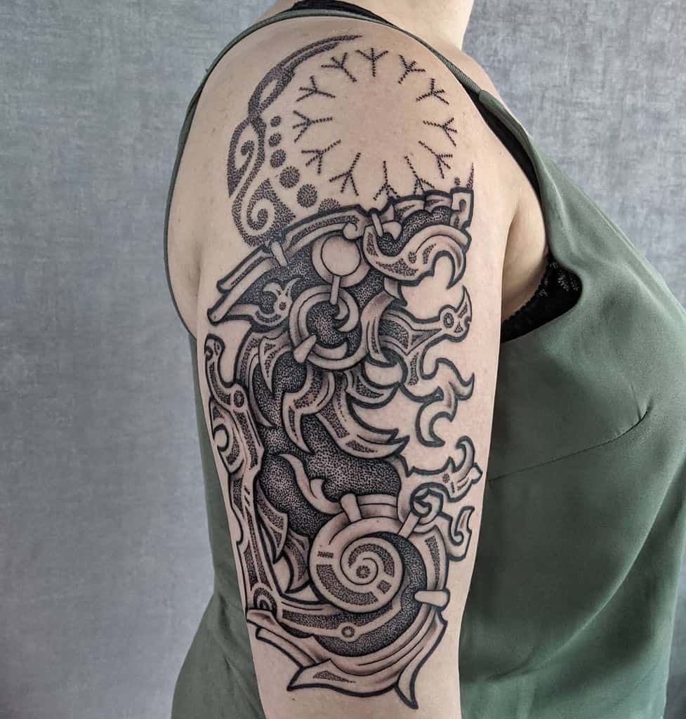 A detailed Celtic-inspired tattoo covering the upper arm, featuring intricate knotwork, swirling patterns, and dot shading