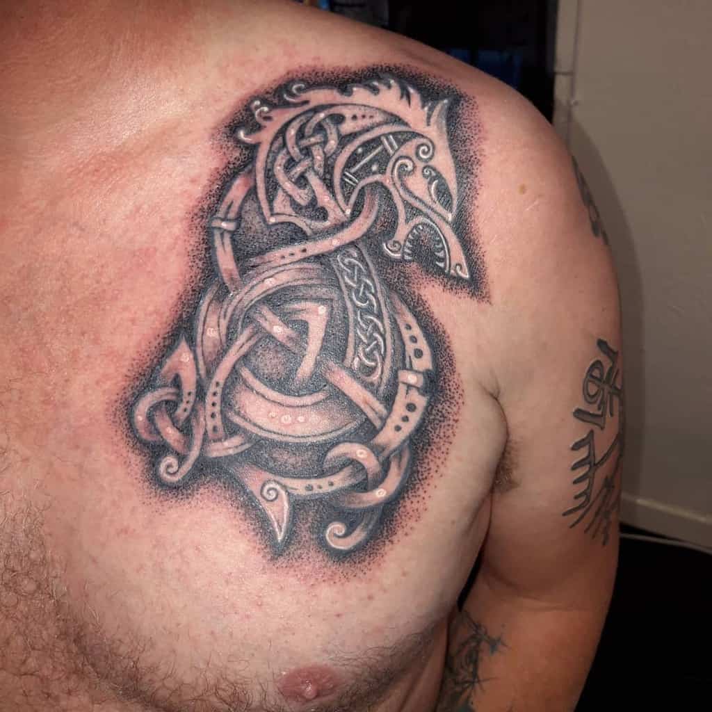 A Celtic-inspired chest tattoo featuring a stylized bird intertwined with intricate knotwork and dot shading, creating a bold and artistic design