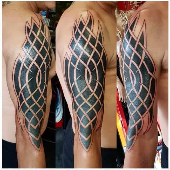 A Celtic tribal tattoo design that wraps around the upper arm, showcasing intricate interwoven knot patterns with bold black shading