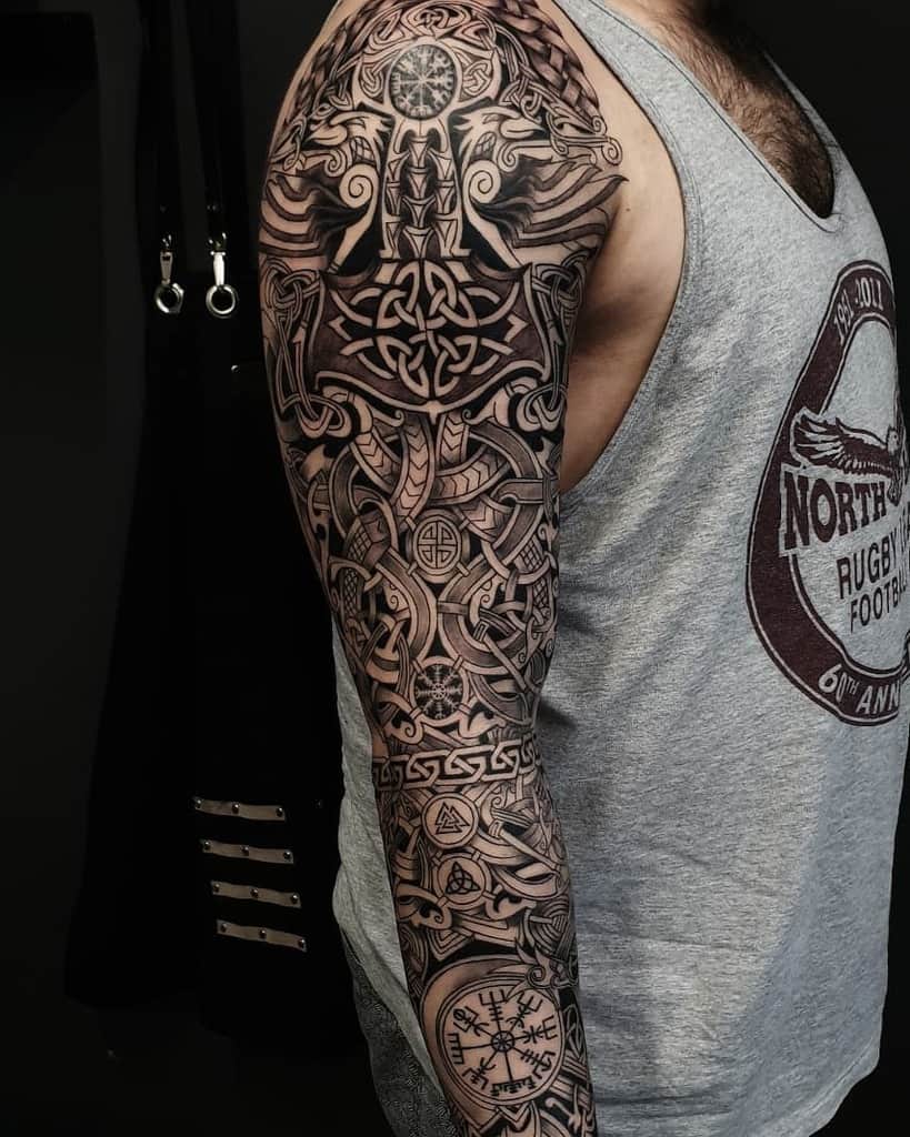 A detailed full-sleeve tattoo featuring complex Celtic knotwork, the Vegvisir symbol, runic designs, and Norse mythology elements throughout