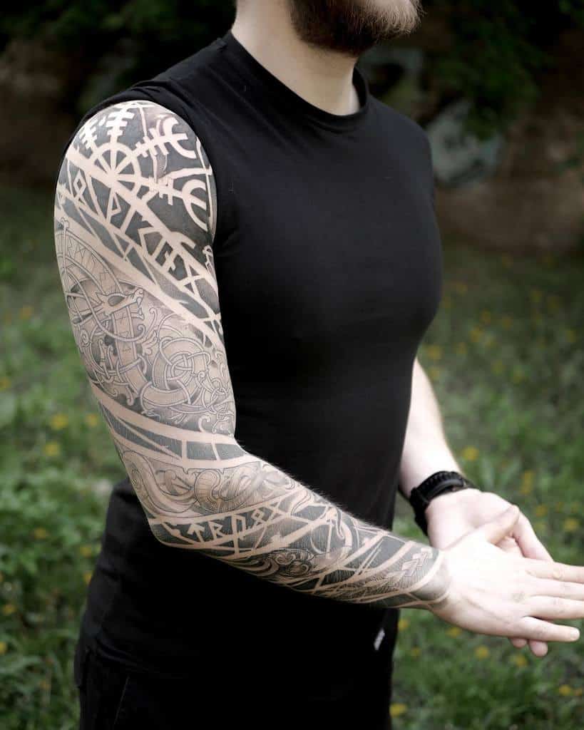 A full-sleeve tattoo featuring intricate Nordic and Celtic patterns, with knotwork, runes, and geometric designs flowing seamlessly across the arm
