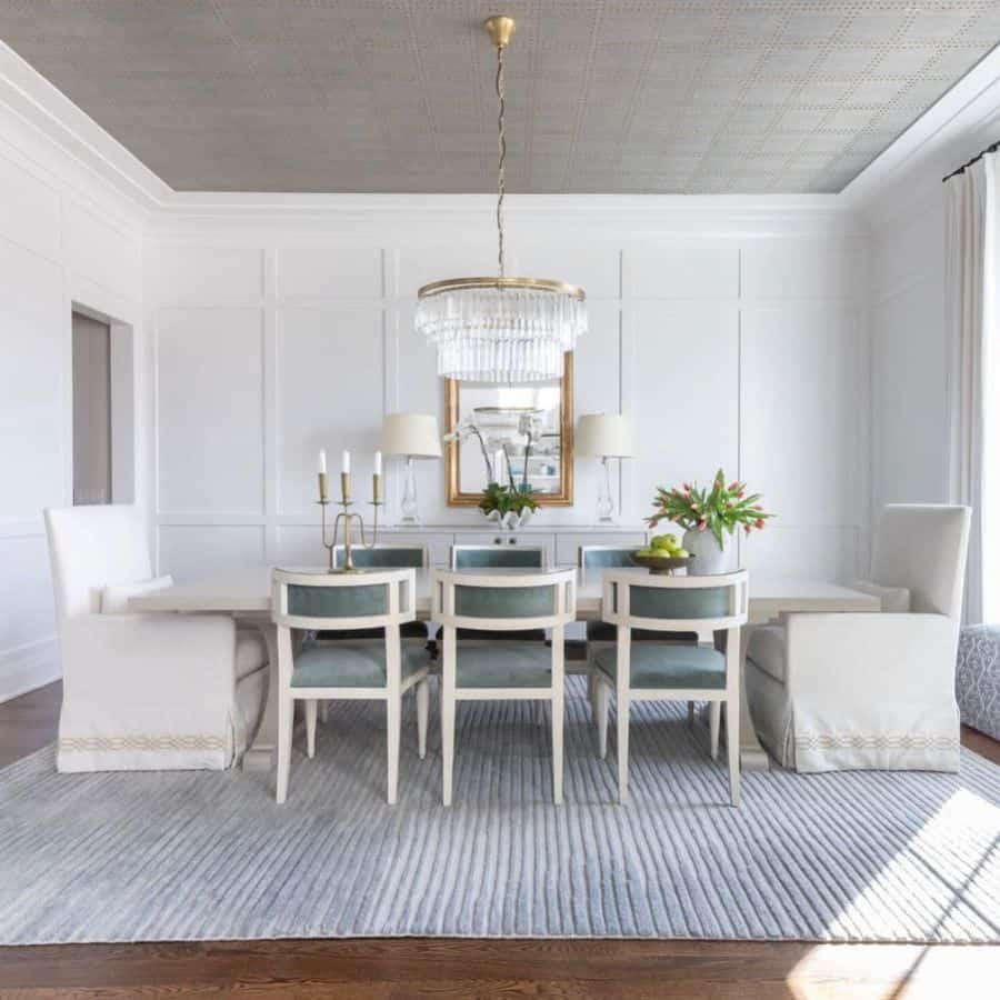 large spacious dining room long table chairs gray rug low hanging chandelier