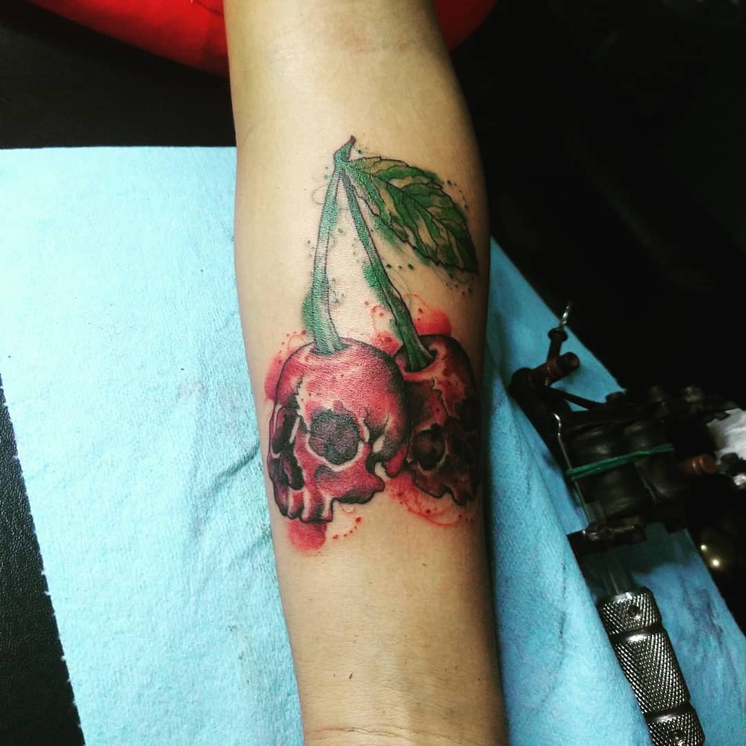 Tattoo of cherries with skulls on an arm