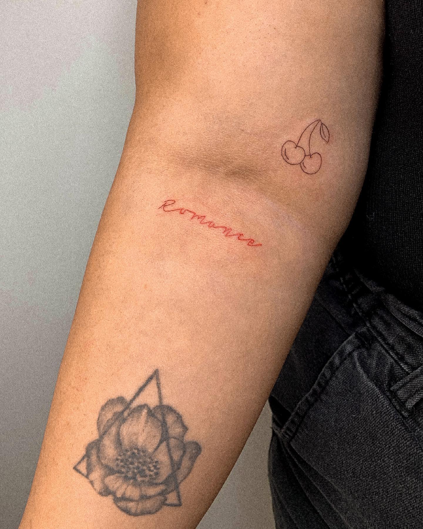 A forearm featuring cherry blossoms, a scripted quote, and flower tattoos