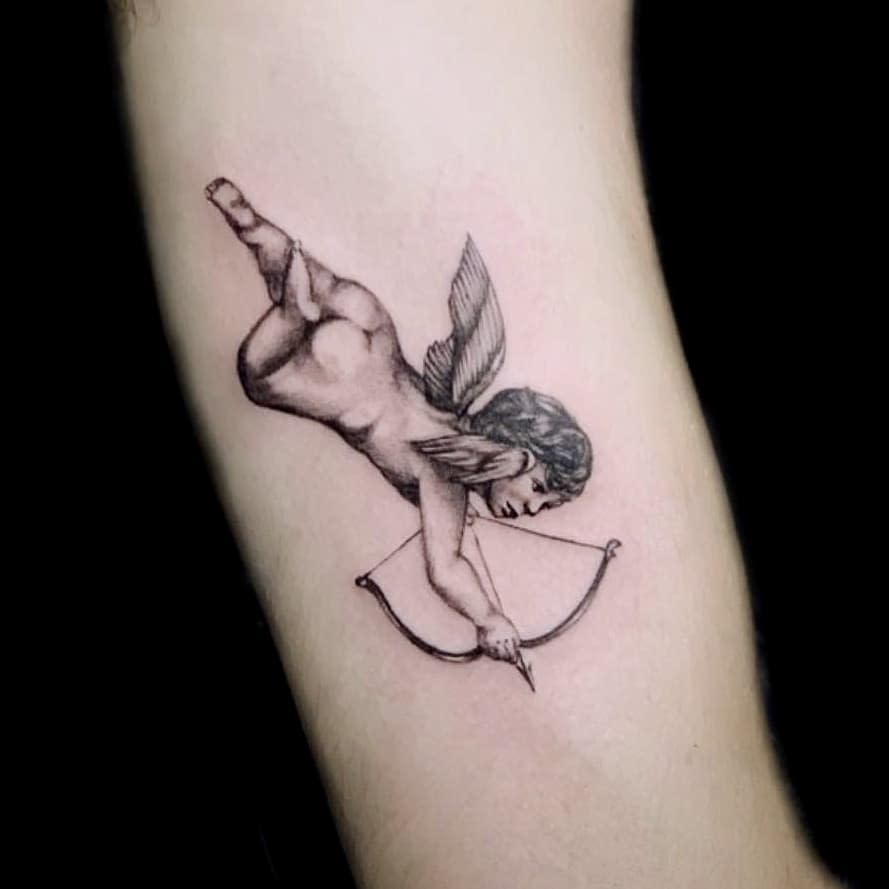 Tattoo of a winged cherub aiming a bow and arrow on an arm