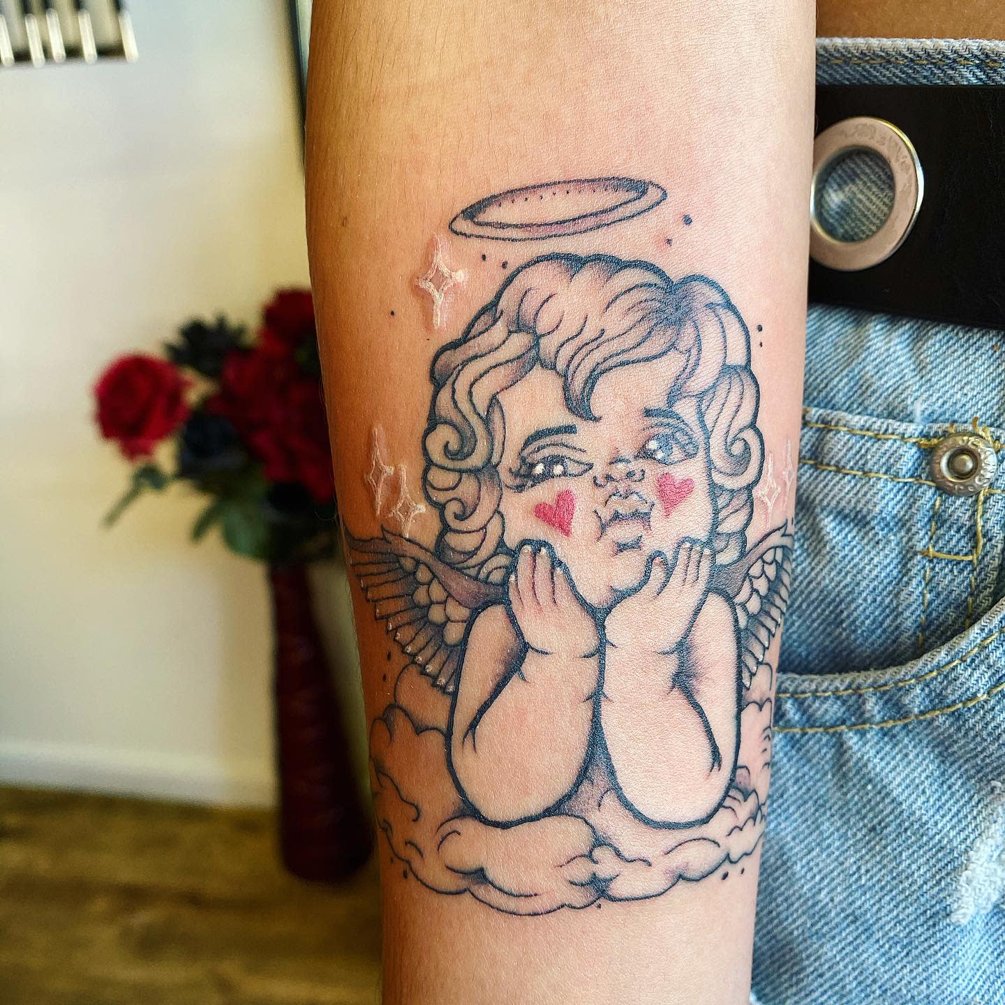 Tattoo of a cherub with wings and halo on an arm
