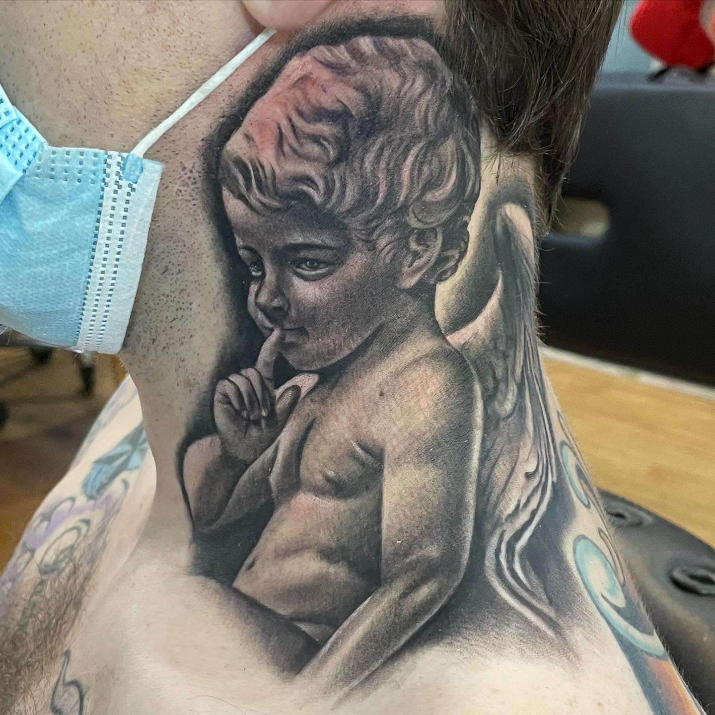 Tattoo of a thoughtful cherub on the side of a neck