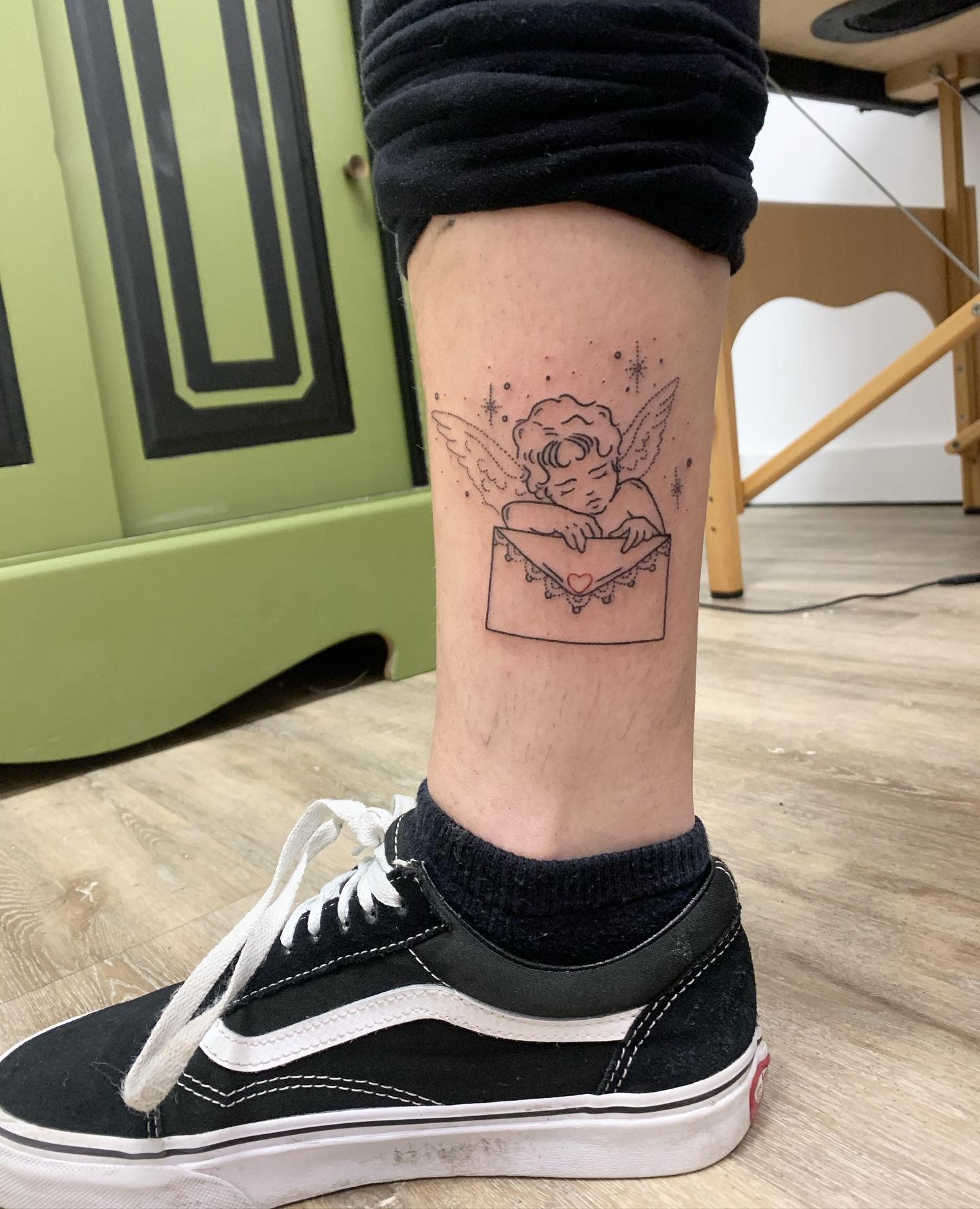 Tattoo on lower leg of a cherub holding a letter