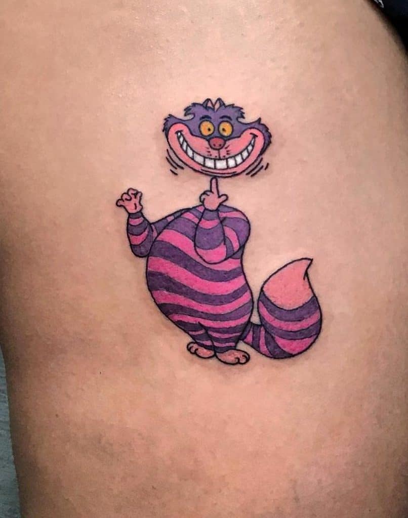 Colorful tattoo of the Cheshire Cat from Alice in Wonderland, with his signature mischievous grin, striped purple and pink body, and playful pose
