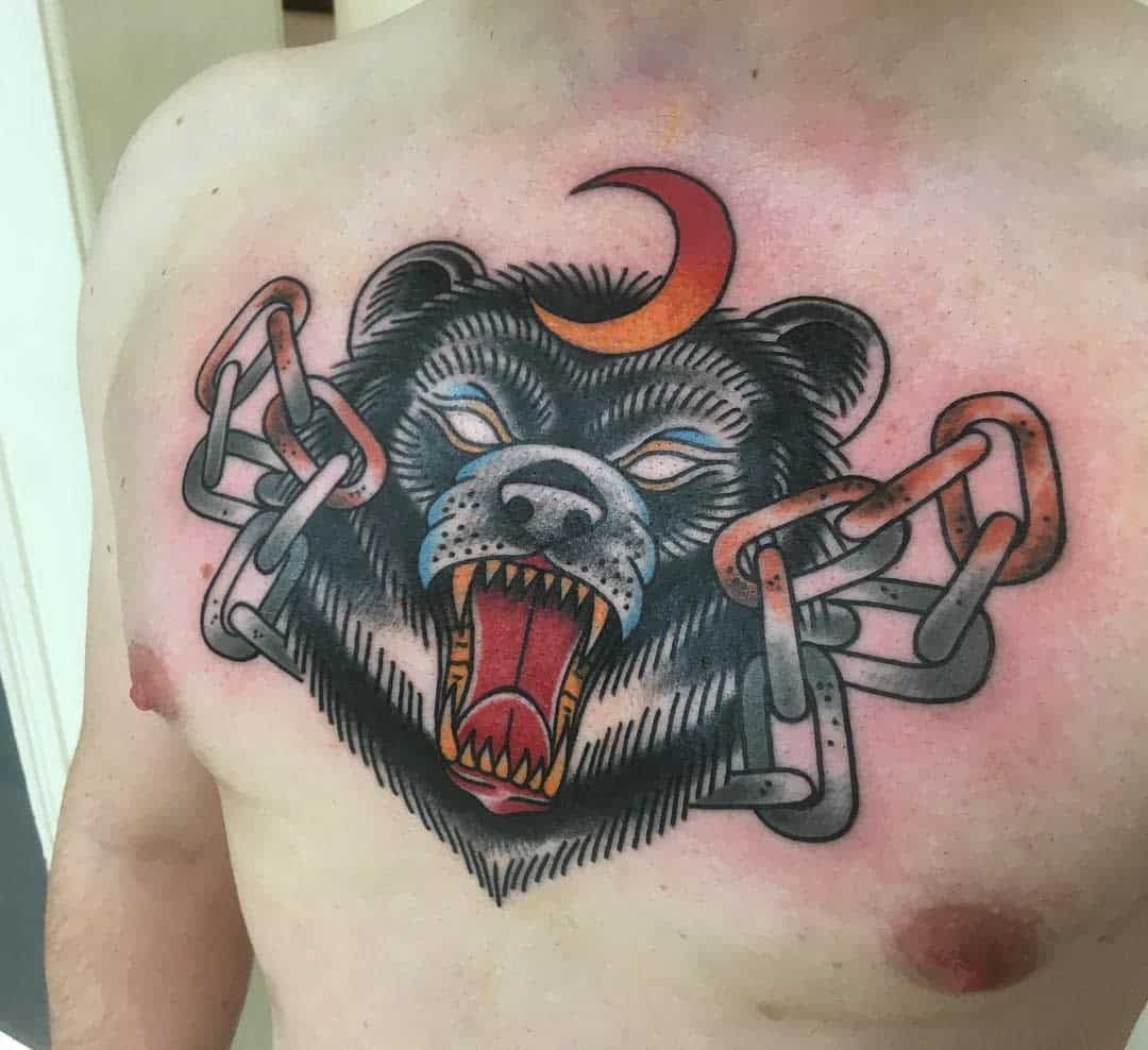 Chest tattoo featuring a roaring bear, a crescent moon, and chains wrapped around its neck