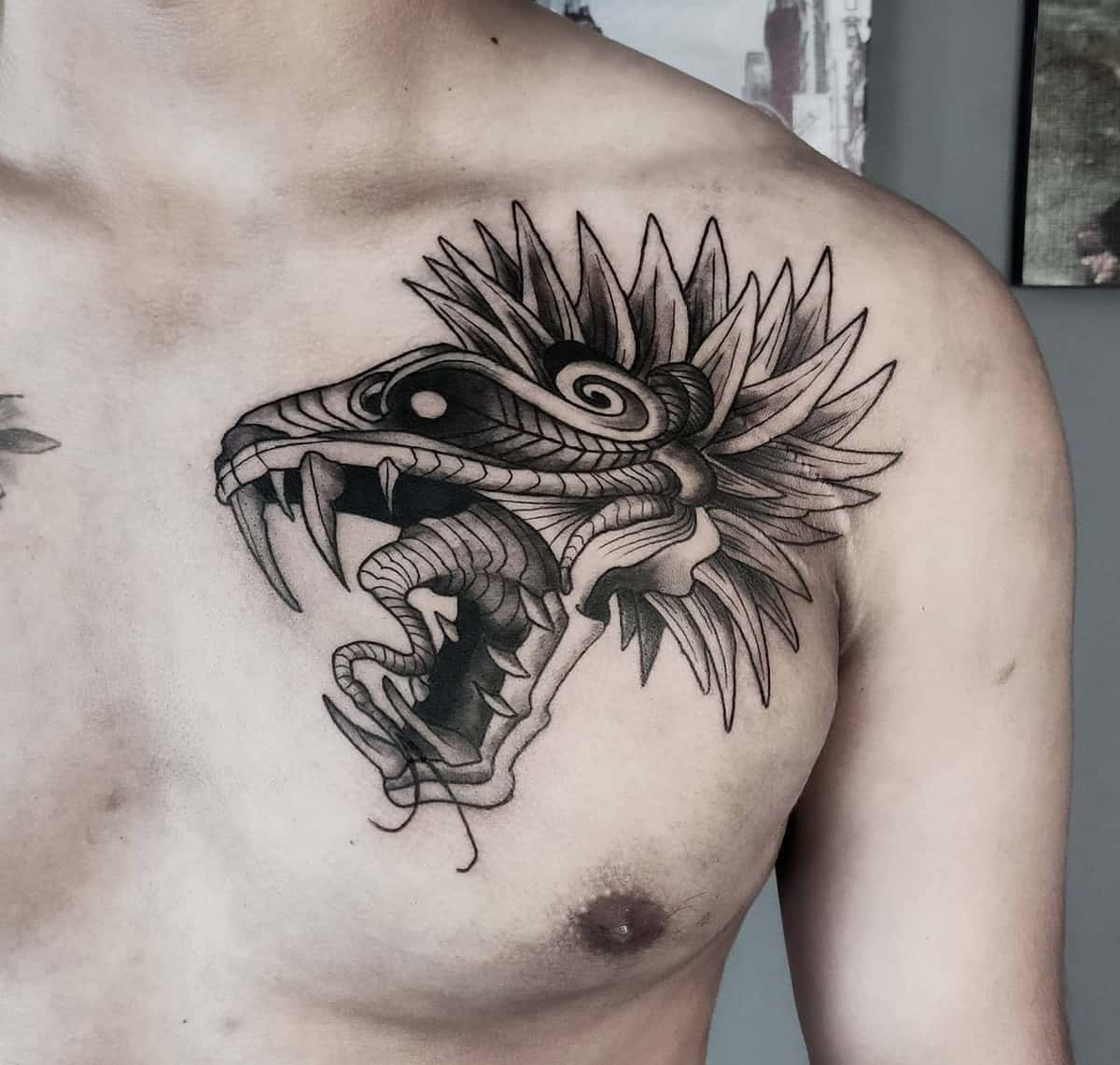 Quetzalcoatl chest tattoo with intricate linework and sharp feathered serpent details