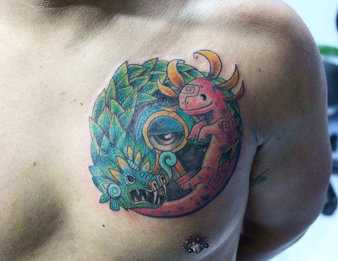 Colorful Quetzalcoatl chest tattoo featuring a vibrant circular design with a serpent and lizard