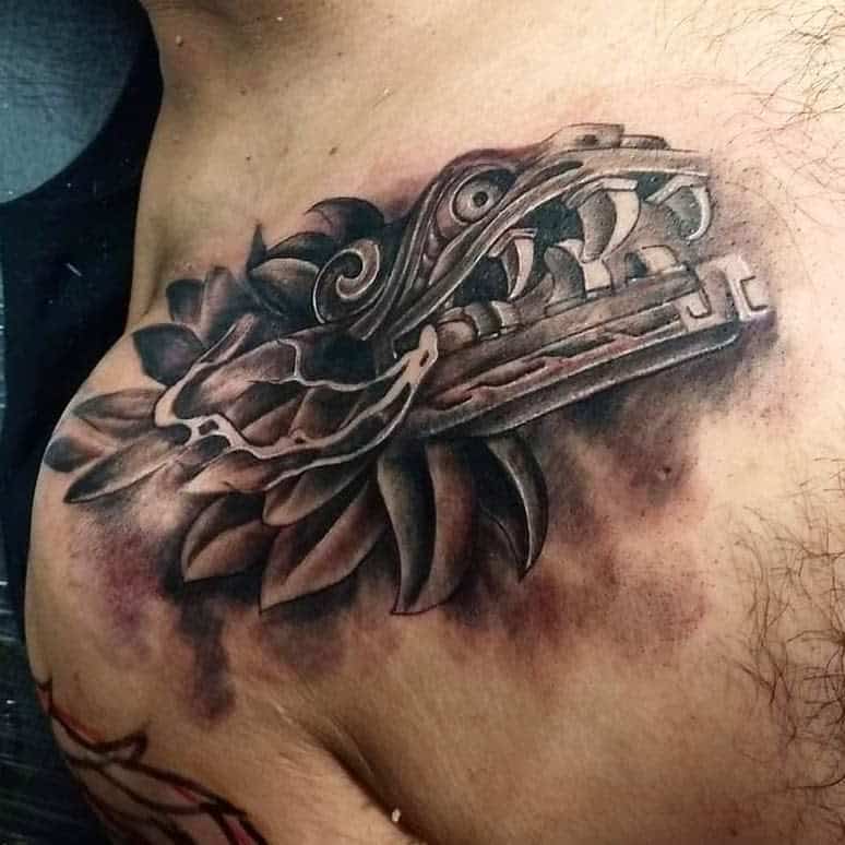 Quetzalcoatl chest tattoo in black and gray, featuring a fierce serpent head with detailed feathers
