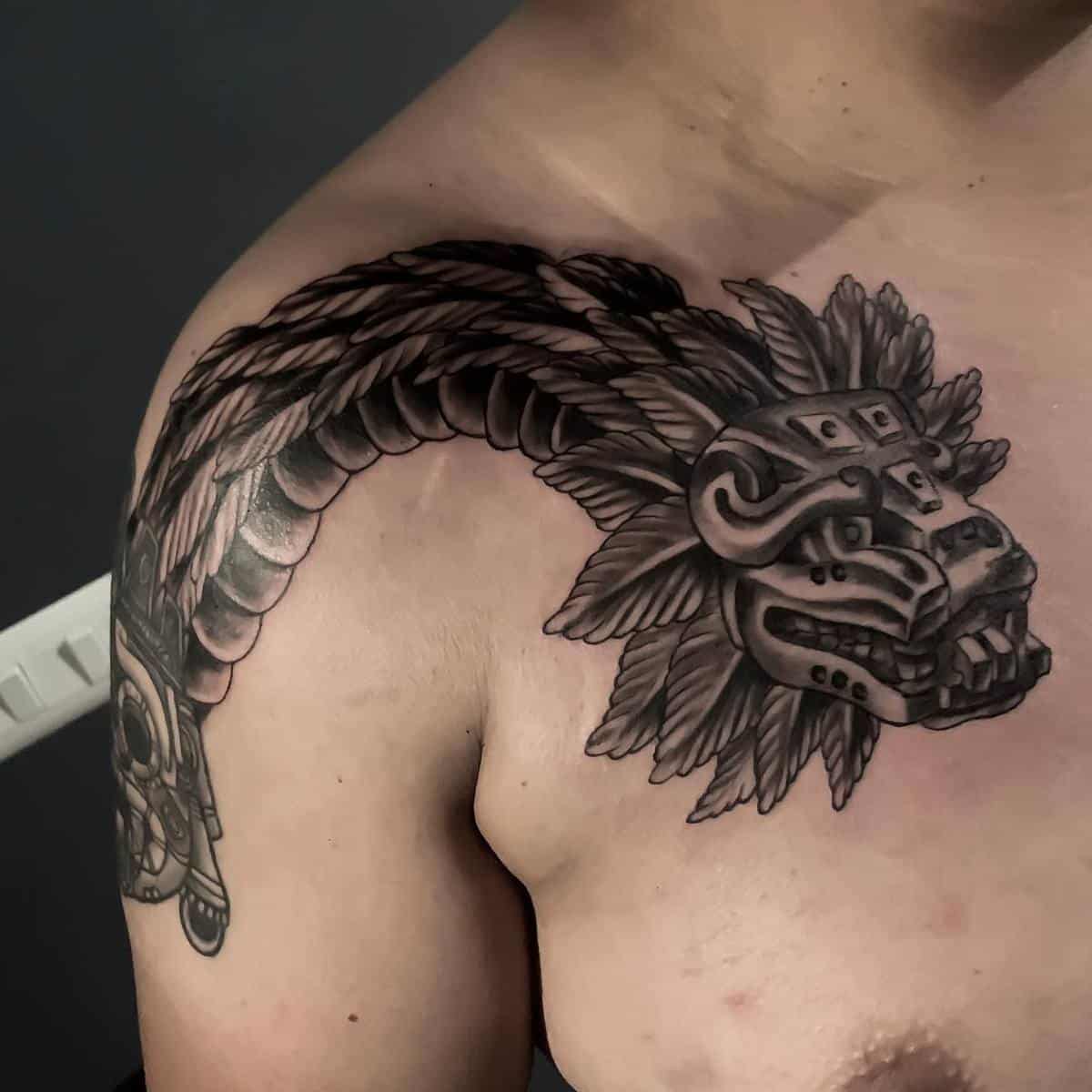 Large Quetzalcoatl tattoo with a detailed feathered serpent head and body wrapping around the shoulder