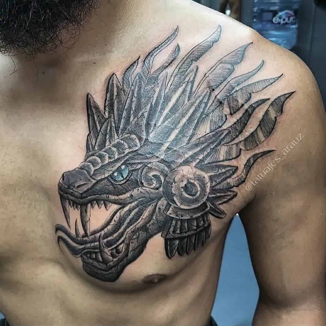 Black ink Quetzalcoatl tattoo with a detailed feathered serpent head and body wrapping across the shoulder