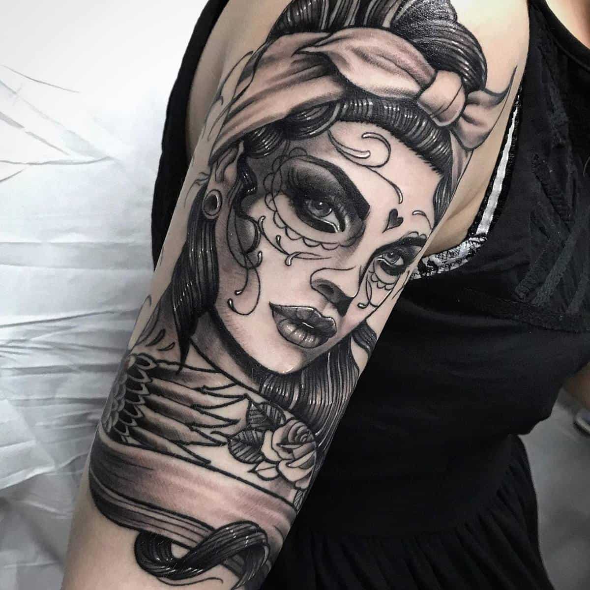 Detailed tattoo of a woman with Catrina makeup, adorned with a headscarf, roses, and bold eyeliner, blending life and death symbolism