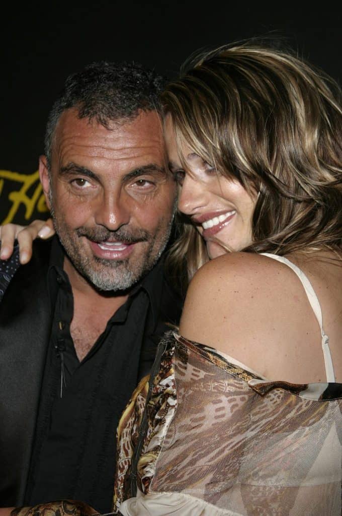 An image with Christian Audigier wearing black shirt with his wife hugging him