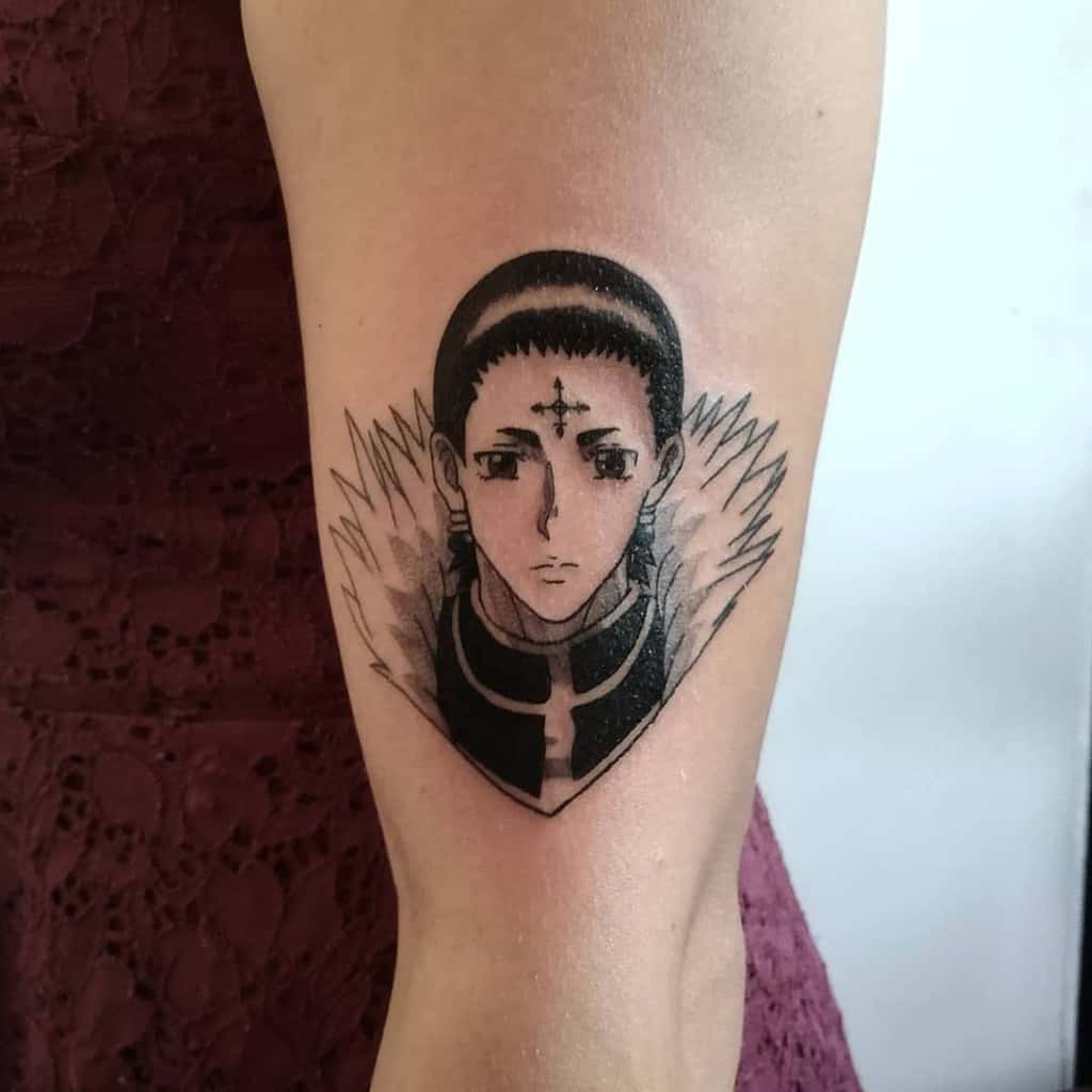 Detailed black-and-grey tattoo of Chrollo Lucilfer from Hunter x Hunter, featuring his calm expression and iconic cross on the forehead