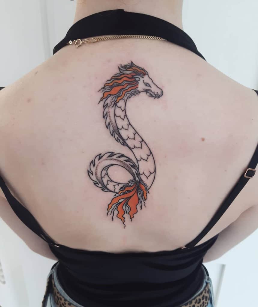Tattoo of a dragon with orange accents on a woman's upper back