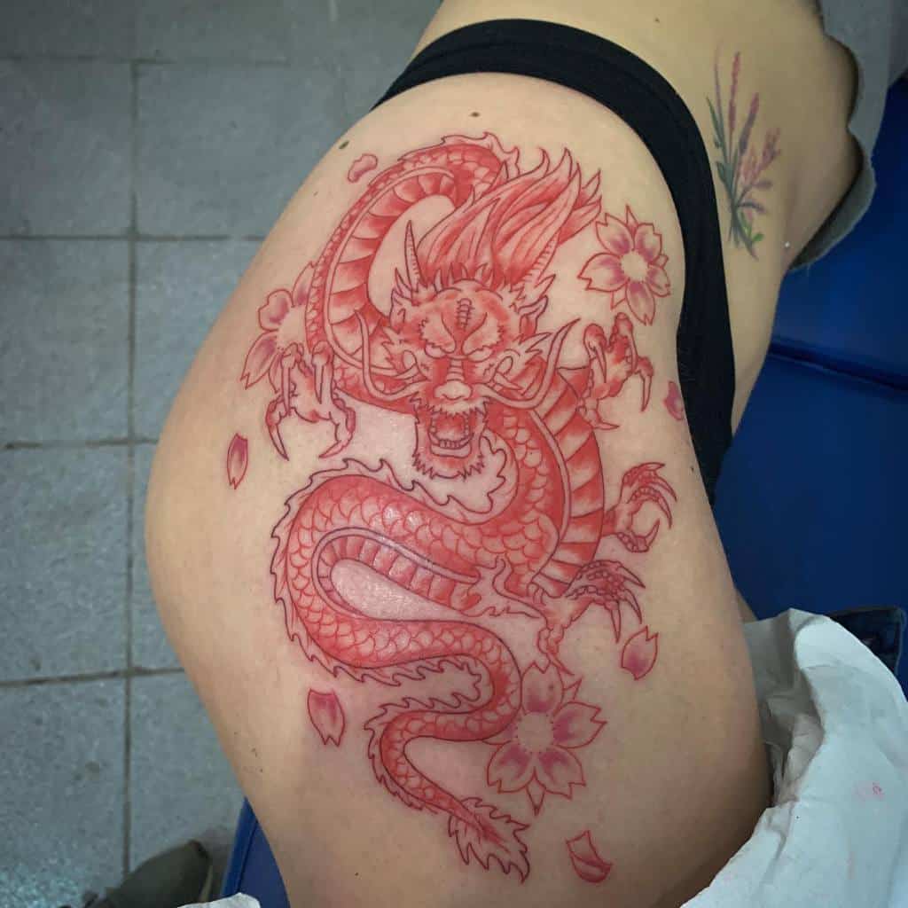 Red dragon and cherry blossom tattoo on a woman's upper leg