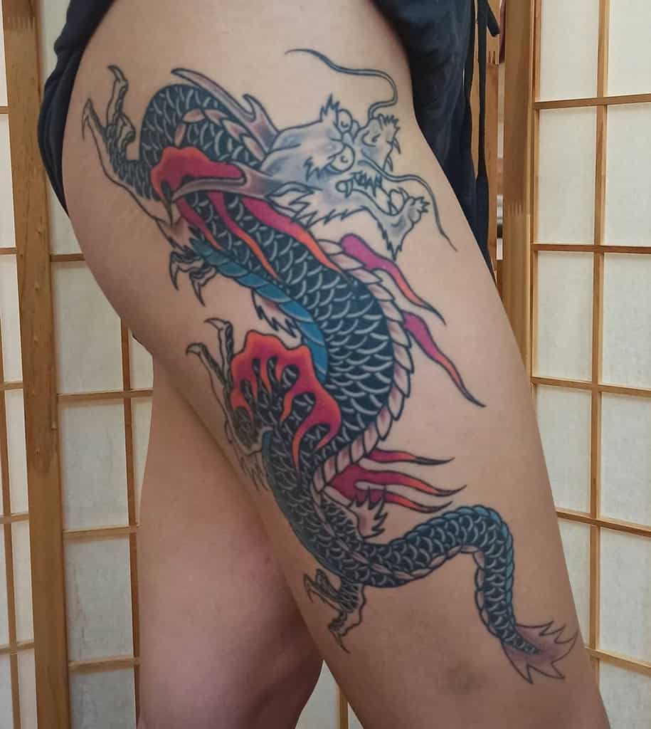 Tattoo of a colorful dragon on a woman's thigh