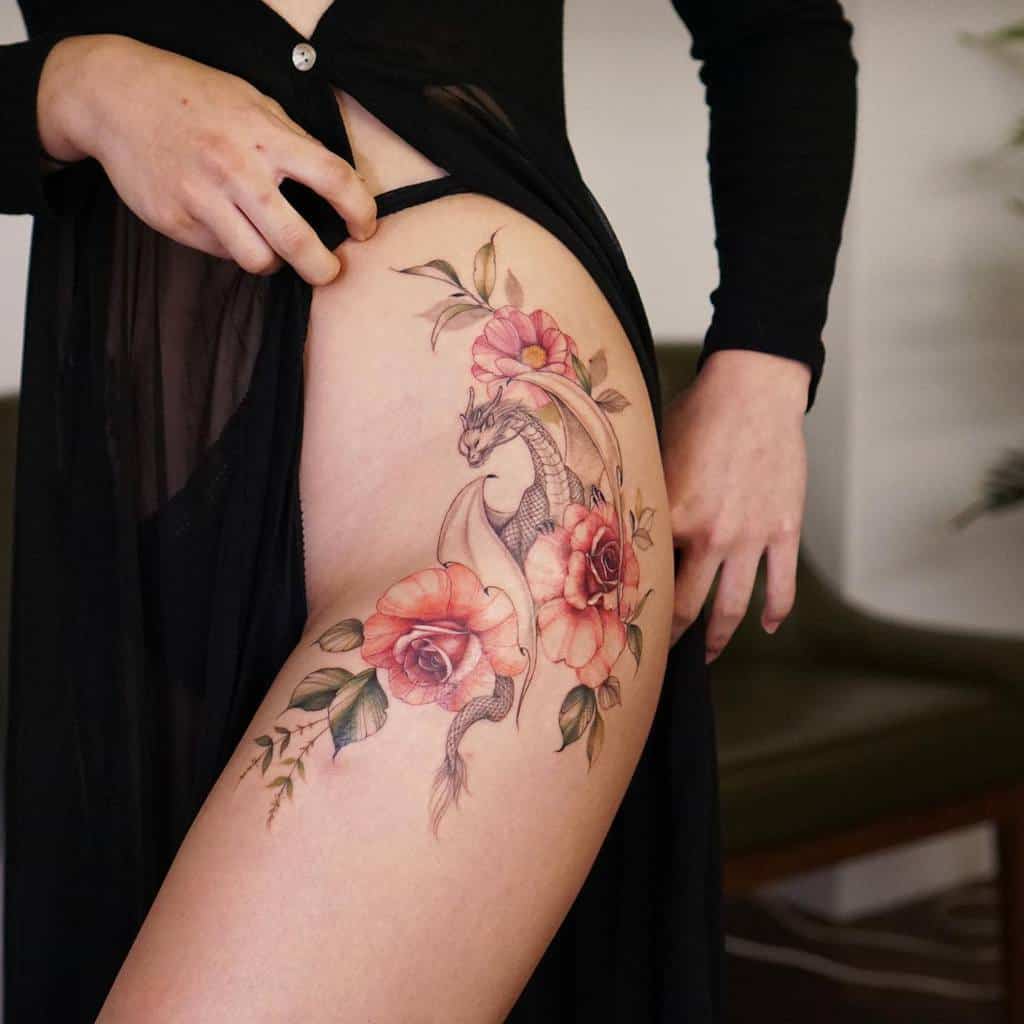Woman displaying a thigh tattoo of a dragon intertwined with roses and leaves