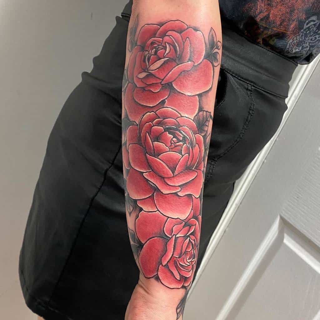 Tattoo of three large red roses beautifully cascading down a person's forearm, creating the elegant beginning of a floral sleeve