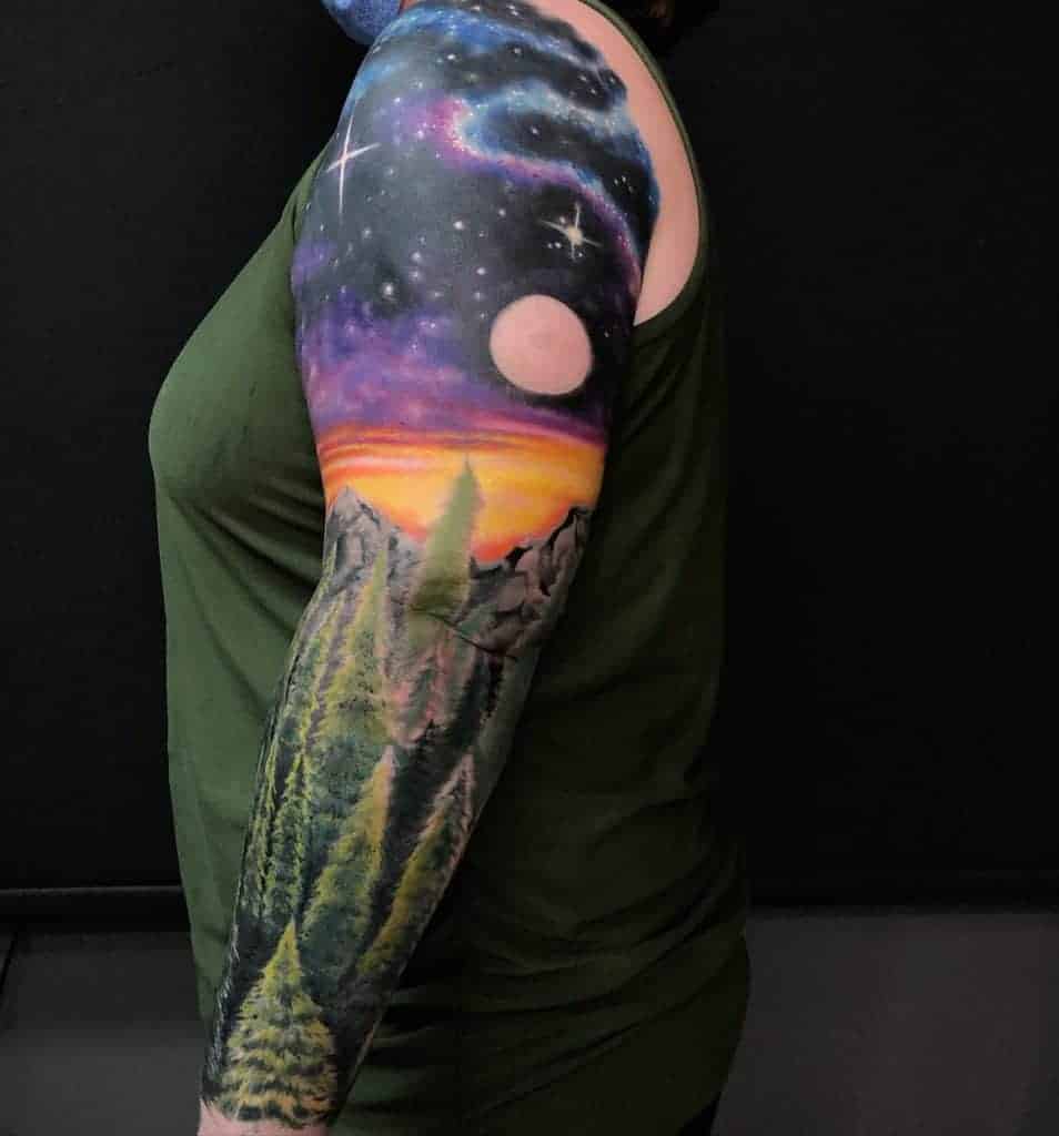 Person with a forest and galaxy-themed sleeve tattoo