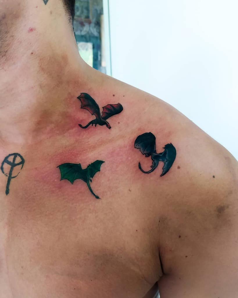 Three small dragon tattoos on a man's upper chest and shoulder